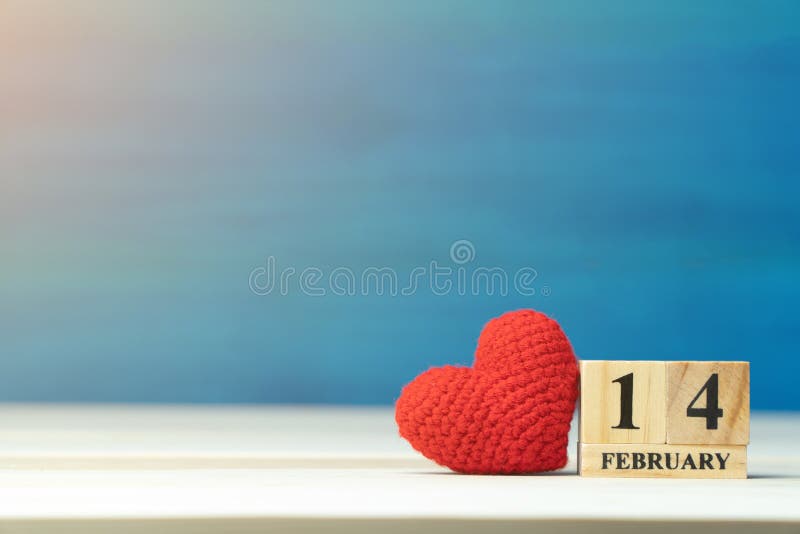 Het concept van de Dag van valentijnskaarten de hand maakt tot garen rood hart naast houten scheurkalender geplaatst op Valentijn