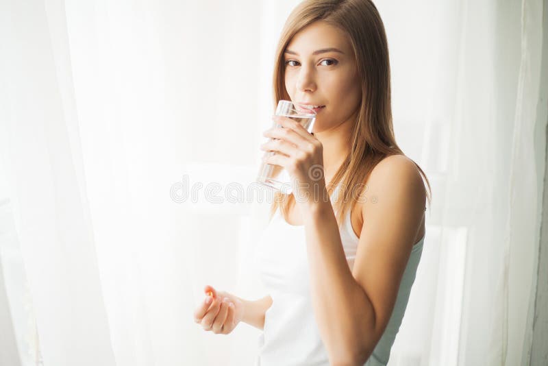 Het concept van de gezondheid De jong pil van de vrouwenholding en glas water royalty-vrije stock foto Het concept van de gezondheid De jong pil van de vrouwenholding en glas water royalty-vrije stock foto