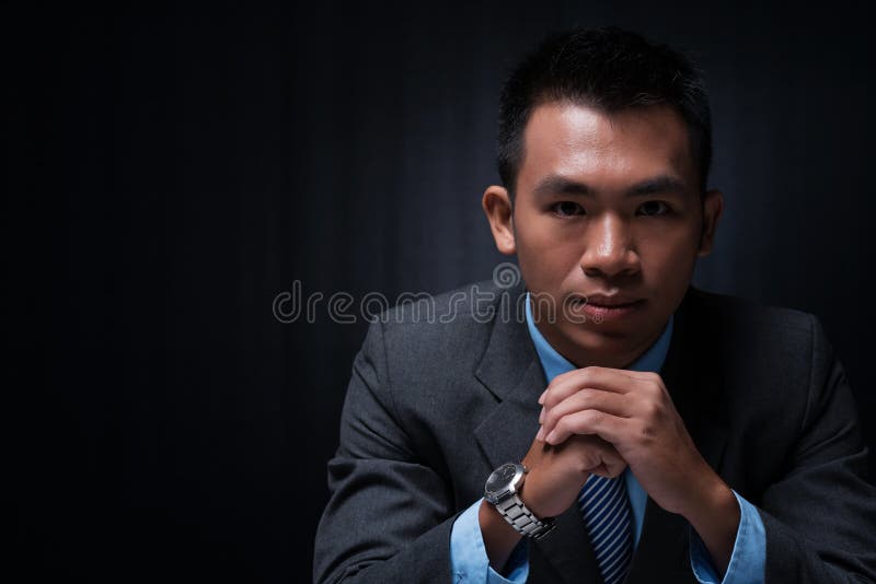 Copy-spaced portrait of a young businessman thinking over the business strategy over a black background. Copy-spaced portrait of a young businessman thinking over the business strategy over a black background