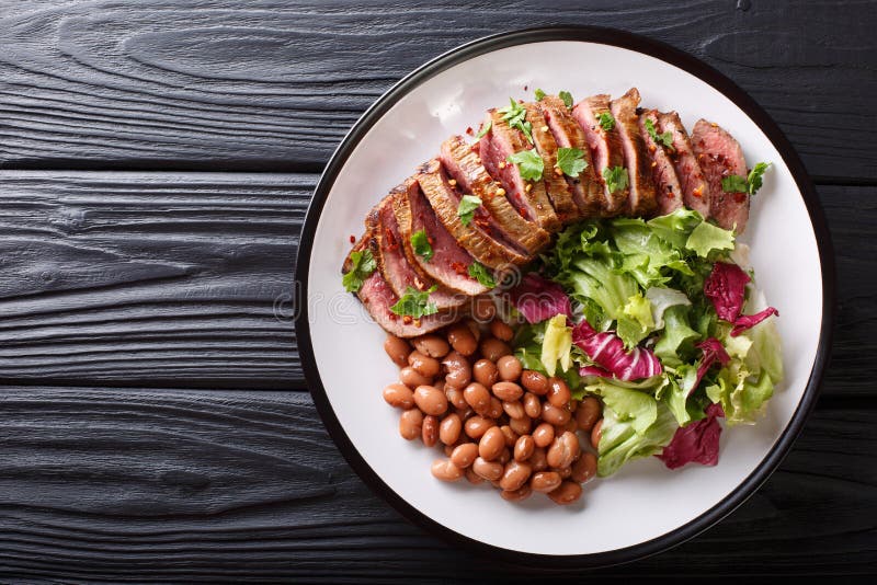 Het dienen van geroosterd rundvleeslapje vlees met verse salade en bonenclose-up o stock afbeeldingen Het dienen van geroosterd rundvleeslapje vlees met verse salade en bonenclose-up o stock afbeeldingen