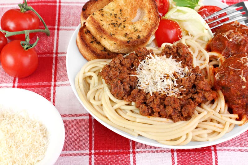 Delicious spaghetti dinner with thick meat sauce, meatballs, salad and garnished with shredded parmesan cheese. Delicious spaghetti dinner with thick meat sauce, meatballs, salad and garnished with shredded parmesan cheese.