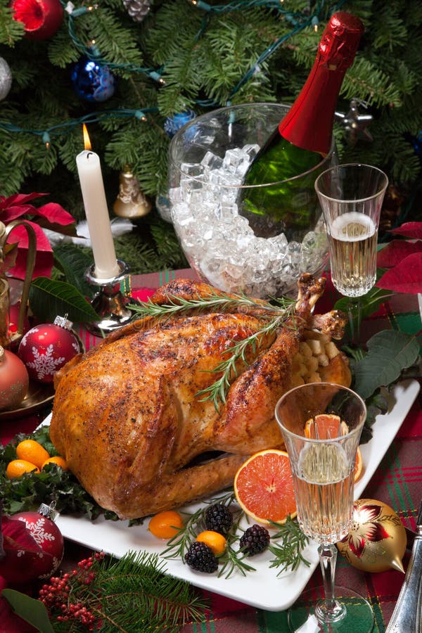 Roasted turkey with fresh fruits, flutes of champagne, Christmas tree, candles, and decorations. Roasted turkey with fresh fruits, flutes of champagne, Christmas tree, candles, and decorations