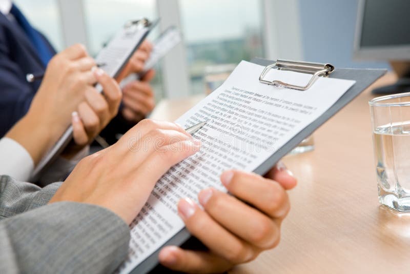 Close-up of female hand over paper reading business document. Close-up of female hand over paper reading business document