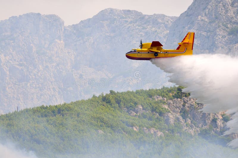Het droping water van het vliegtuig op brand stock afbeelding Het droping water van het vliegtuig op brand stock afbeelding