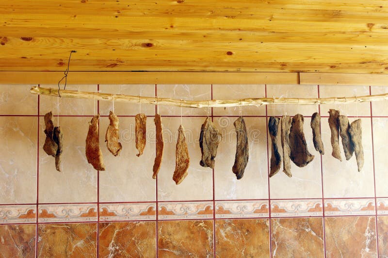 Het eigengemaakte gekruide droge vlees hangen op houten staaf royalty-vrije stock foto's Het eigengemaakte gekruide droge vlees hangen op houten staaf royalty-vrije stock foto's