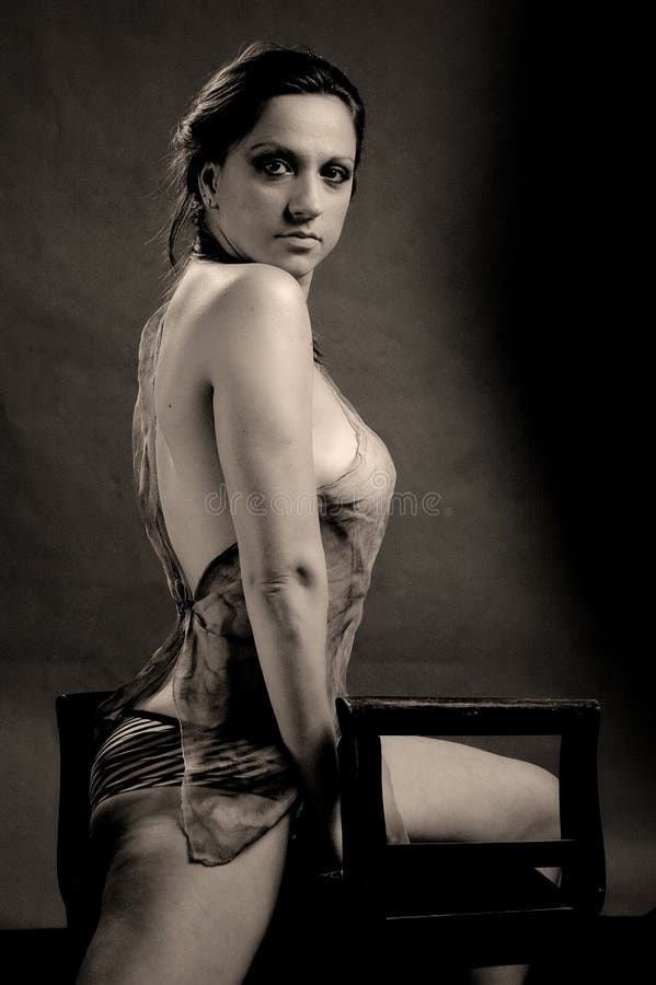 Het erotische vrouw stellen op een stoel stock fotografie Het erotische vrouw stellen op een stoel stock fotografie