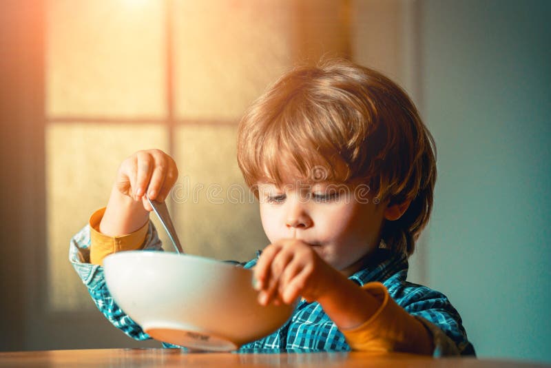 Het eten van het jonge geitje Weinig jongen die ontbijt in de keuken hebben Leuk kind die ontbijt thuis eten Baby het eten royalty-vrije stock afbeelding Het eten van het jonge geitje Weinig jongen die ontbijt in de keuken hebben Leuk kind die ontbijt thuis eten Baby het eten royalty-vrije stock afbeelding
