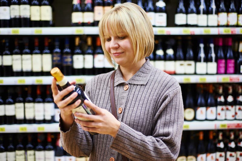 Het etiket van de vrouwenlezing op fles wijn in opslag royalty-vrije stock afbeelding Het etiket van de vrouwenlezing op fles wijn in opslag royalty-vrije stock afbeelding