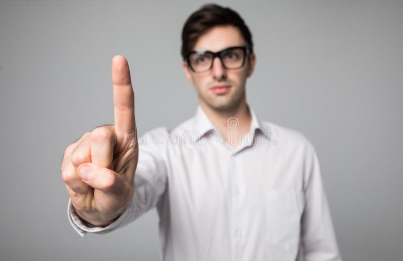 Het gebaar van de mensenwijsvinger, die wit overhemd op grijze achtergrond dragen stock afbeelding Het gebaar van de mensenwijsvinger, die wit overhemd op grijze achtergrond dragen stock afbeelding