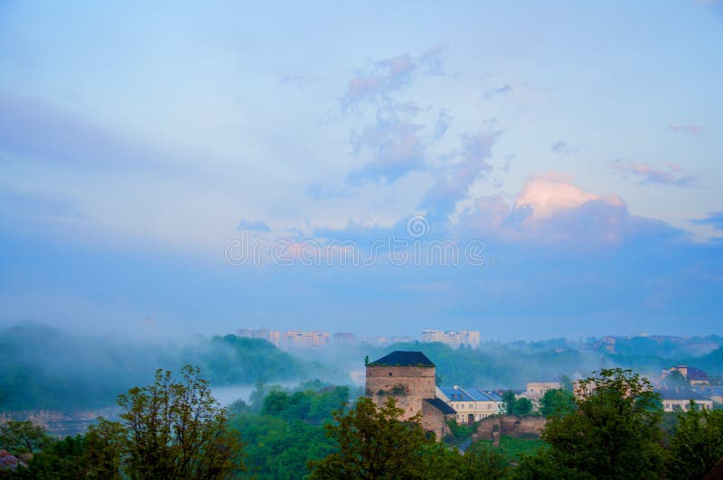 Het gelijk maken van oude stad in de mist Grote steentoren Schemering in kamenetz-Podolsk Lage wolken stock fotografie Het gelijk maken van oude stad in de mist Grote steentoren Schemering in kamenetz-Podolsk Lage wolken stock fotografie