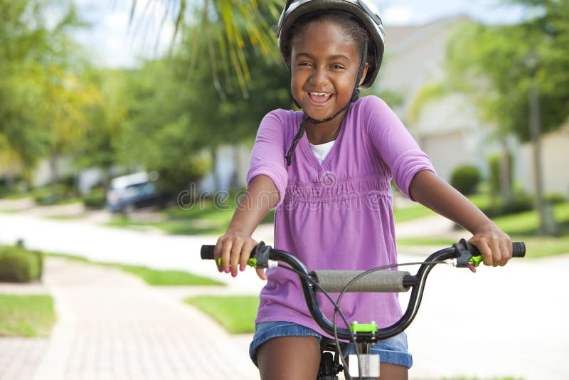 Het gelukkige Afrikaanse Amerikaanse het Berijden van het Meisje Glimlachen van de Fiets stock foto Het gelukkige Afrikaanse Amerikaanse het Berijden van het Meisje Glimlachen van de Fiets stock foto