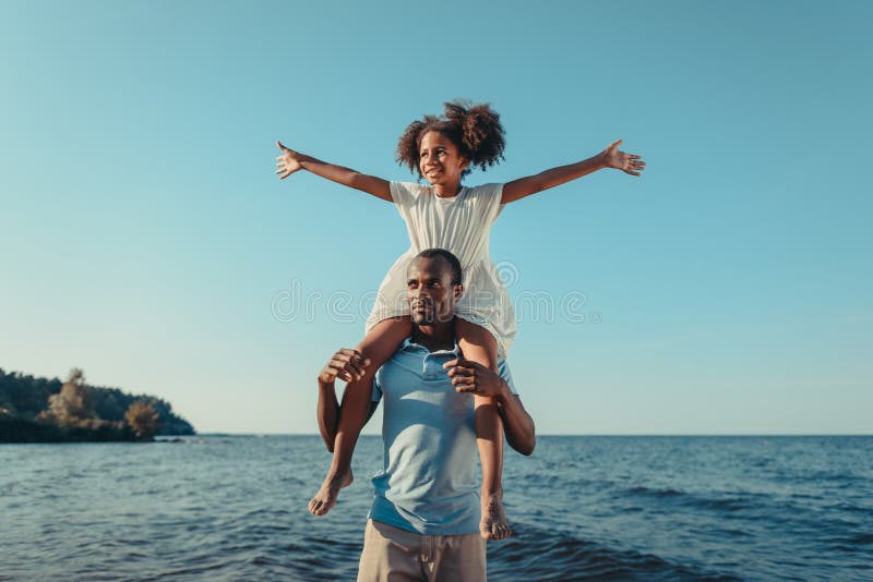 het gelukkige Afrikaanse Amerikaanse vader aanbiddelijk dragen weinig dochter op hals