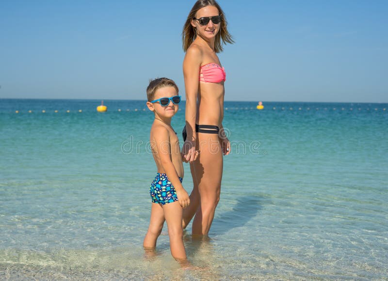 Het gelukkige familie ontspannen door het overzees Gelukkige familie die bij strand in de zomer rusten moeder met babyjongen die stock fotografie Het gelukkige familie ontspannen door het overzees Gelukkige familie die bij strand in de zomer rusten moeder met babyjongen die stock fotografie