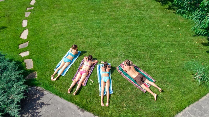 Het gelukkige familie ontspannen door zwembad, de luchthommelmening van hierboven van ouders en de jonge geitjes hebben pret op v stock fotografie Het gelukkige familie ontspannen door zwembad, de luchthommelmening van hierboven van ouders en de jonge geitjes hebben pret op v stock fotografie