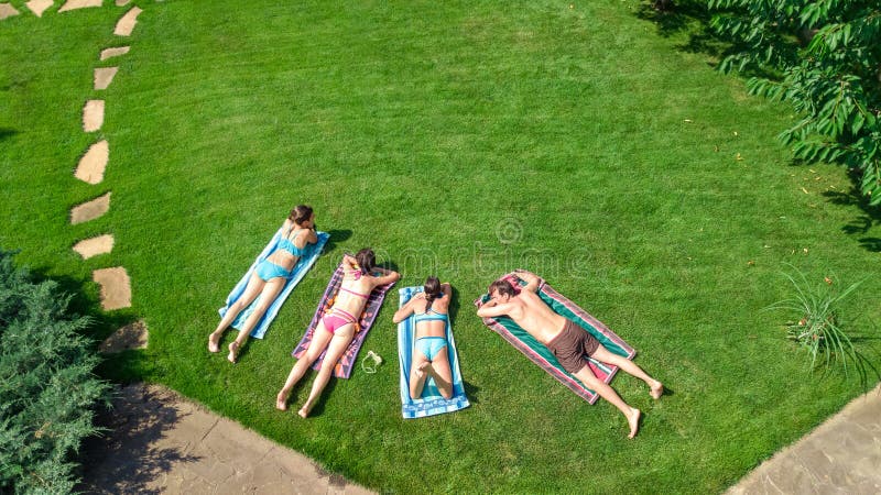 Het gelukkige familie ontspannen door zwembad, de luchthommelmening van hierboven van ouders en de jonge geitjes hebben pret op v stock foto Het gelukkige familie ontspannen door zwembad, de luchthommelmening van hierboven van ouders en de jonge geitjes hebben pret op v stock foto