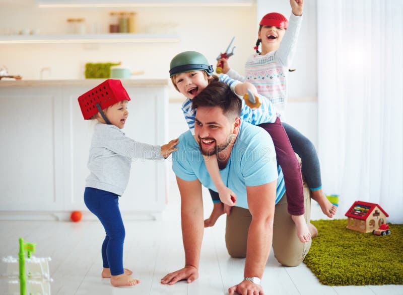 Het gelukkige familie spelen die samen thuis, op vader berijden stock foto's Het gelukkige familie spelen die samen thuis, op vader berijden stock foto's