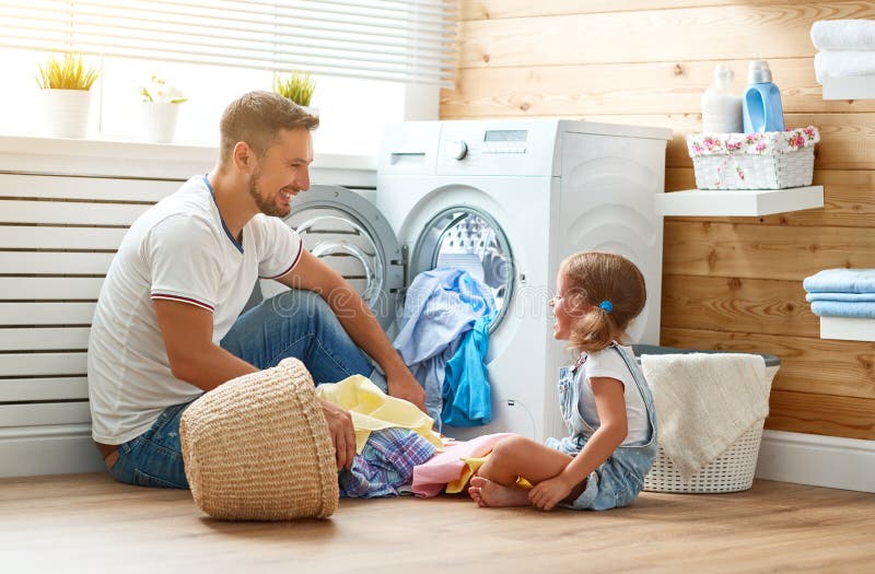 Happy family men father householder and child daughter in laundry with washing machine. Happy family men father householder and child daughter in laundry with washing machine