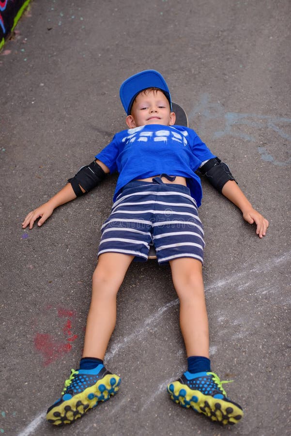Het gelukkige jonge jongen ontspannen op zijn skateboard royalty-vrije stock afbeelding Het gelukkige jonge jongen ontspannen op zijn skateboard royalty-vrije stock afbeelding