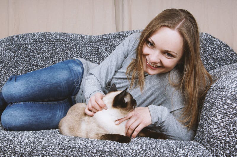 Het gelukkige jonge vrouw ontspannen op laag met kat royalty-vrije stock foto Het gelukkige jonge vrouw ontspannen op laag met kat royalty-vrije stock foto