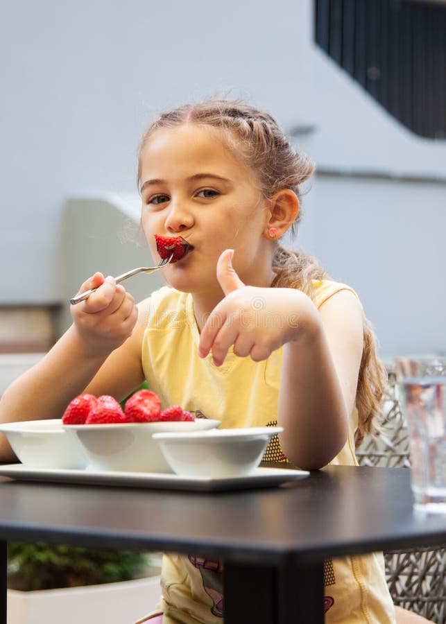 Het gelukkige kindmeisje eet aardbeien in de zomer, Jonge leuke smil royalty-vrije stock afbeelding Het gelukkige kindmeisje eet aardbeien in de zomer, Jonge leuke smil royalty-vrije stock afbeelding