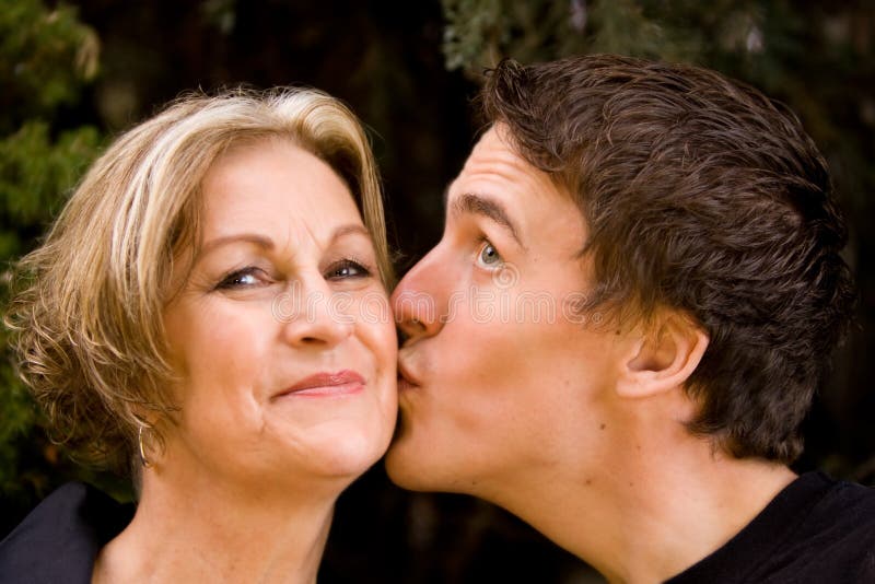 Het gelukkige mamma glimlachen en zoon die kus geven royalty-vrije stock fotografie Het gelukkige mamma glimlachen en zoon die kus geven royalty-vrije stock fotografie