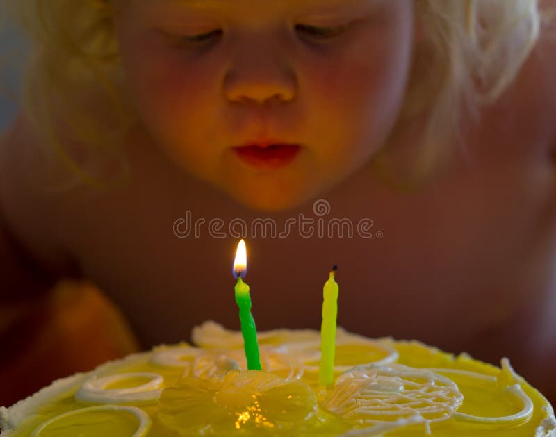 Het gelukkige meisje blazen uit schouwt op een cake op haar verjaardag stock foto Het gelukkige meisje blazen uit schouwt op een cake op haar verjaardag stock foto