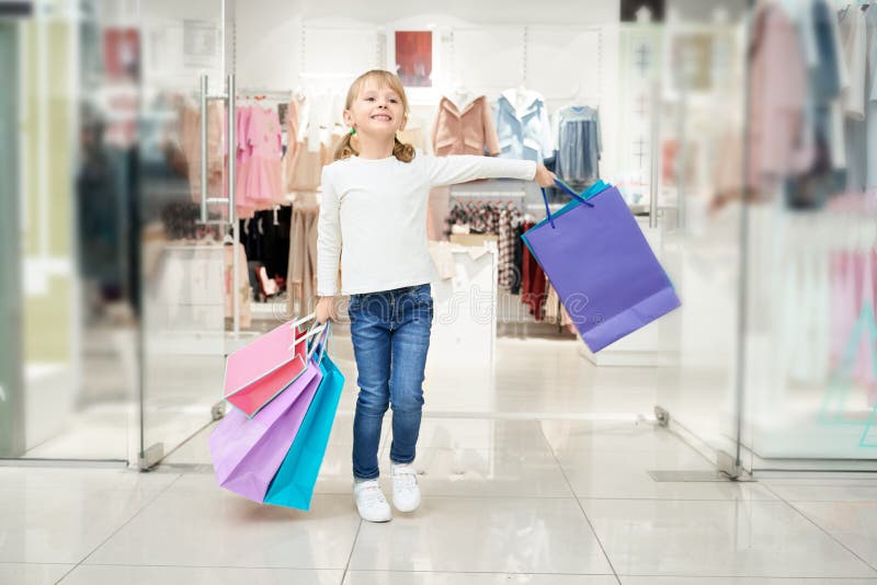 Het gelukkige meisje stellen in winkelend centrum met vele zakken royalty-vrije stock foto Het gelukkige meisje stellen in winkelend centrum met vele zakken royalty-vrije stock foto