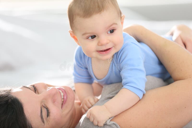 Het gelukkige moeder spelen met haar baby op het bed stock fotografie Het gelukkige moeder spelen met haar baby op het bed stock fotografie