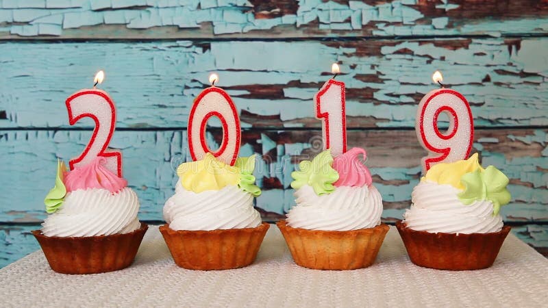 Het gelukkige nieuwe jaar van 2019, aantalkaarsen op cupcakes met blauwe houten achtergrond