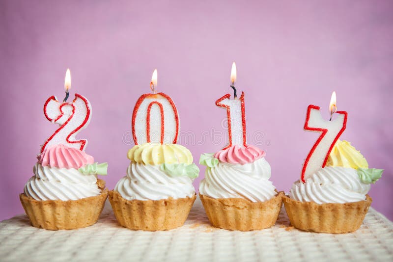 Het gelukkige nieuwe jaar van 2017 met kaarsen op cakes met roze achtergrond stock foto's Het gelukkige nieuwe jaar van 2017 met kaarsen op cakes met roze achtergrond stock foto's