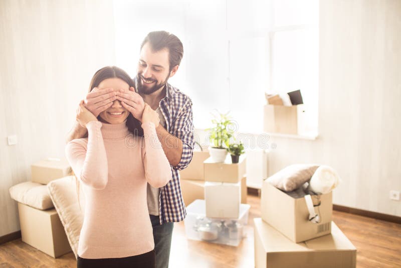 Het gelukkige paar bevindt zich binnen hun nieuw huis De jonge mens heeft ogen aan zijn vrouw gesloten Hij bereidde verrassing vo royalty-vrije stock afbeelding Het gelukkige paar bevindt zich binnen hun nieuw huis De jonge mens heeft ogen aan zijn vrouw gesloten Hij bereidde verrassing vo royalty-vrije stock afbeelding