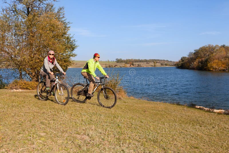Het gelukkige paar die van de bergfiets in openlucht cirkelen royalty-vrije stock afbeelding Het gelukkige paar die van de bergfiets in openlucht cirkelen royalty-vrije stock afbeelding
