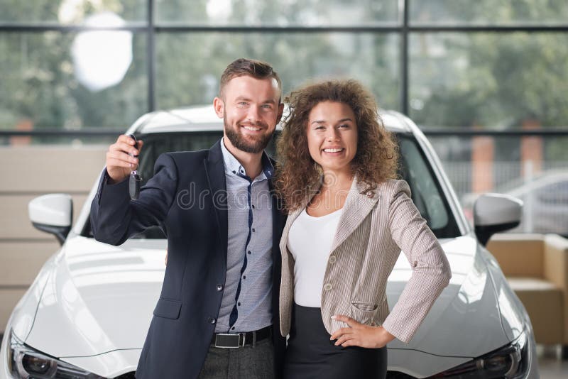 Het gelukkige paar stellen met nieuwe witte auto en sleutels stock afbeelding Het gelukkige paar stellen met nieuwe witte auto en sleutels stock afbeelding