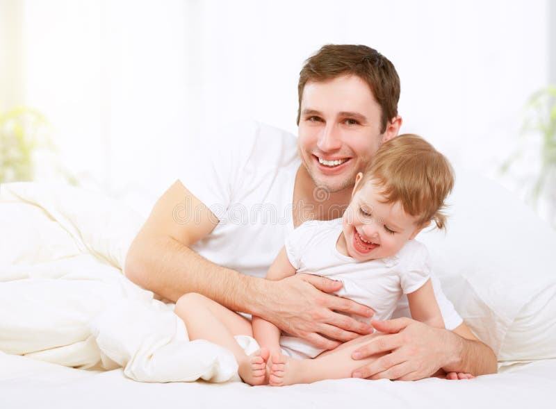 Het gelukkige van de familievader en baby dochter spelen in bed royalty-vrije stock afbeeldingen Het gelukkige van de familievader en baby dochter spelen in bed royalty-vrije stock afbeeldingen