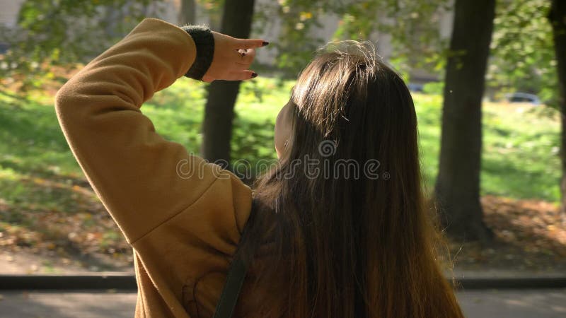 Het gelukkige verbazende Kaukasische meisje met lang haar bekijkt zon en geniet van het op haar gezicht terwijl status in groen