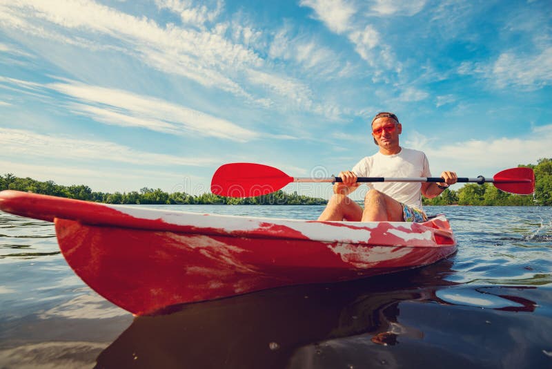 Het gelukkige volwassen mens kayaking op de rivier bij een zonnige ochtend royalty-vrije stock fotografie Het gelukkige volwassen mens kayaking op de rivier bij een zonnige ochtend royalty-vrije stock fotografie