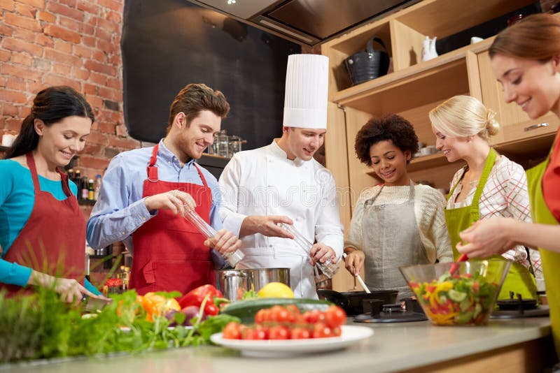 Het gelukkige vrienden en chef-kokkok koken in keuken stock foto Het gelukkige vrienden en chef-kokkok koken in keuken stock foto
