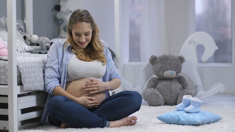 Het gelukkige zwangere vrouwelijke het voelen baby duwen