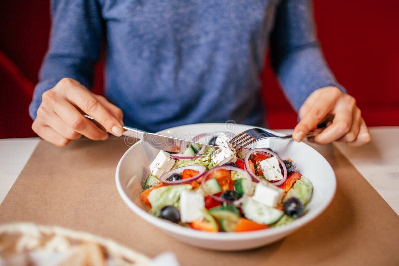 Het gezond eten, op dieet zijn en mensenconcept - sluit omhoog van jonge vrouw die plantaardige Griekse salade thuis op houten et royalty-vrije stock foto Het gezond eten, op dieet zijn en mensenconcept - sluit omhoog van jonge vrouw die plantaardige Griekse salade thuis op houten et royalty-vrije stock foto