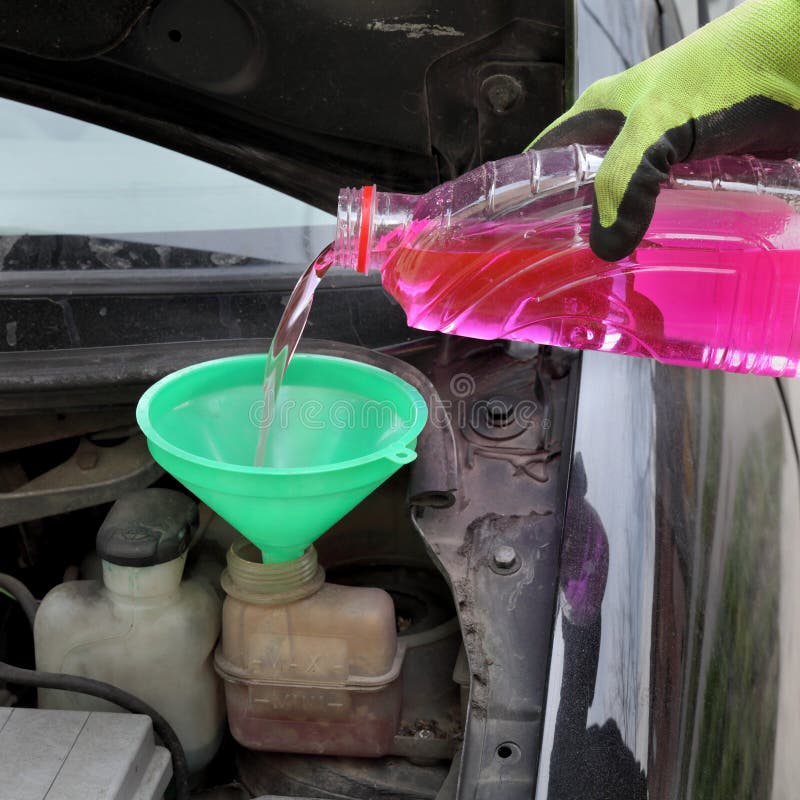 Het gietende antivriesmiddel van de arbeidershand aan auto stock afbeeldingen Het gietende antivriesmiddel van de arbeidershand aan auto stock afbeeldingen