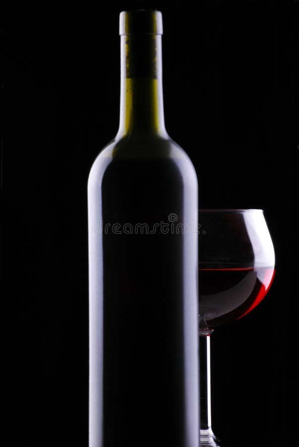 Red Wine Glass behind Bottle on Black Background. Red Wine Glass behind Bottle on Black Background