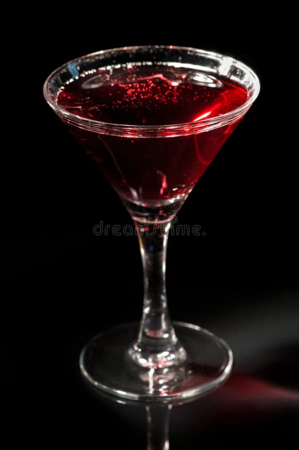 Martini glass with red cocktail of vodka, soda and grape juice isolated on black. Shallow depth of field, focus is on the glass rim. Martini glass with red cocktail of vodka, soda and grape juice isolated on black. Shallow depth of field, focus is on the glass rim.