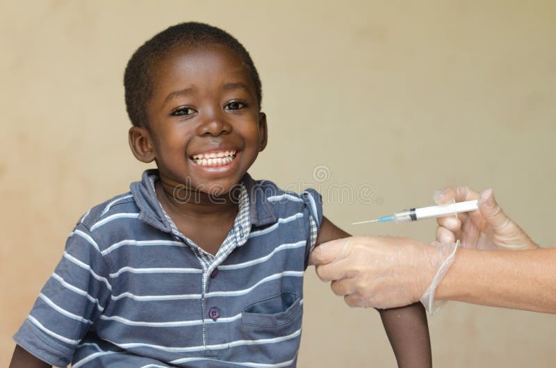 Het glimlachen Afrikaanse jongenszitting terwijl het krijgen van een injectie van een Europese Vrijwilliger stock foto Het glimlachen Afrikaanse jongenszitting terwijl het krijgen van een injectie van een Europese Vrijwilliger stock foto