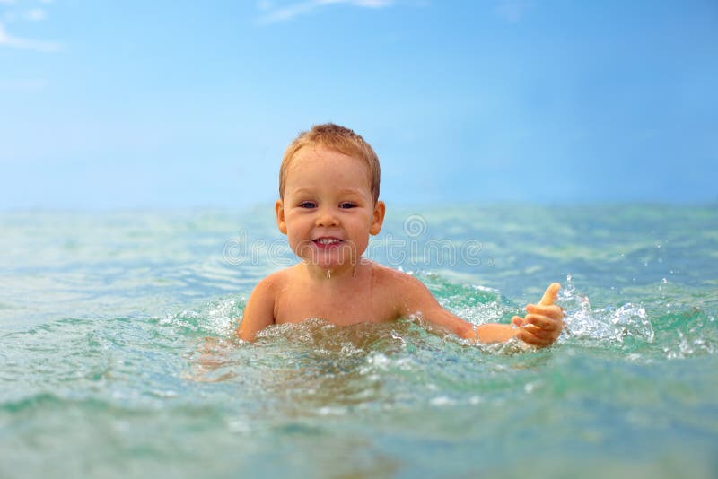 Het glimlachen babyjongen het spelen met overzees water stock afbeelding Het glimlachen babyjongen het spelen met overzees water stock afbeelding
