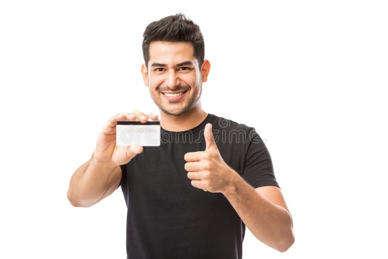 Het glimlachen van de Creditcard van de Jonge Mensenholding terwijl Gesturing omhoog beduimelt royalty-vrije stock fotografie Het glimlachen van de Creditcard van de Jonge Mensenholding terwijl Gesturing omhoog beduimelt royalty-vrije stock fotografie
