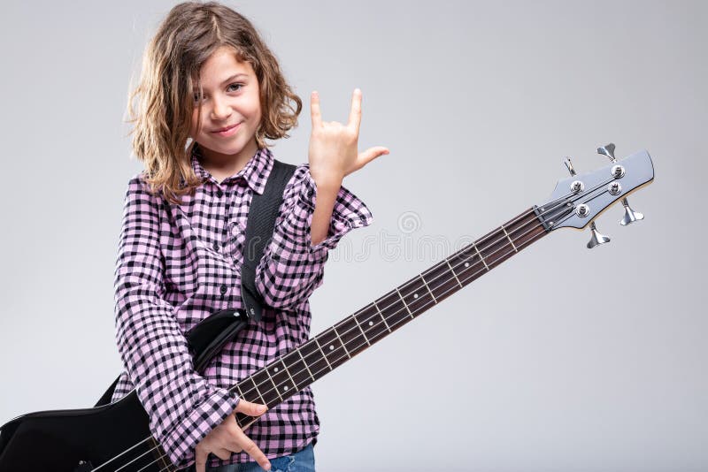 Het glimlachen van meisje het spelen gitaar die een hoornenteken geven royalty-vrije stock afbeeldingen Het glimlachen van meisje het spelen gitaar die een hoornenteken geven royalty-vrije stock afbeeldingen