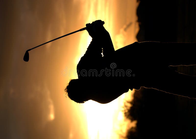 A left handed golfer practices early morning with a beautiful sunrise. A left handed golfer practices early morning with a beautiful sunrise.