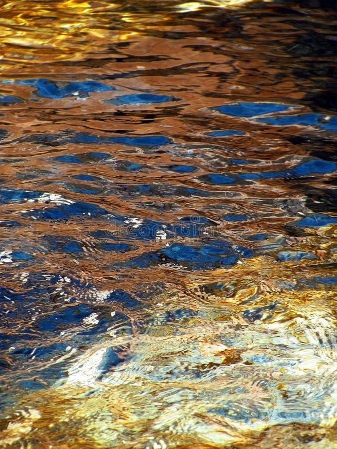 Het golven waterspiegeltextuur met gouden zonlichtbezinningen stock foto Het golven waterspiegeltextuur met gouden zonlichtbezinningen stock foto