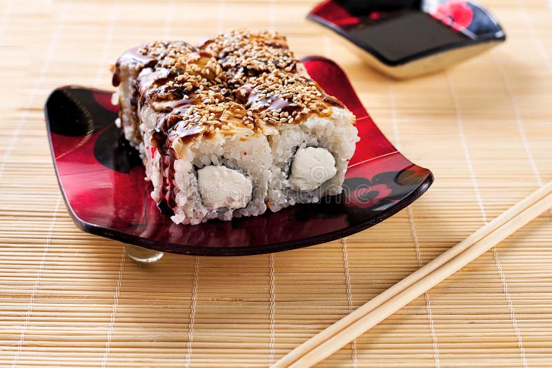 Het gouden broodje van draaksushi met saus op een zwarte plaat royalty-vrije stock fotografie Het gouden broodje van draaksushi met saus op een zwarte plaat royalty-vrije stock fotografie