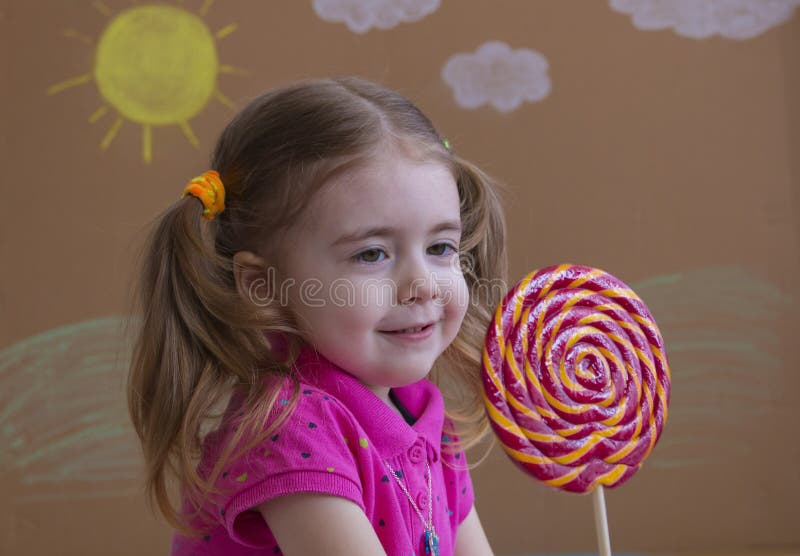 Het grappige kind met suikergoedlolly, gelukkig meisje die grote suikerlolly, jong geitje eten eet snoepjes royalty-vrije stock afbeeldingen Het grappige kind met suikergoedlolly, gelukkig meisje die grote suikerlolly, jong geitje eten eet snoepjes royalty-vrije stock afbeeldingen